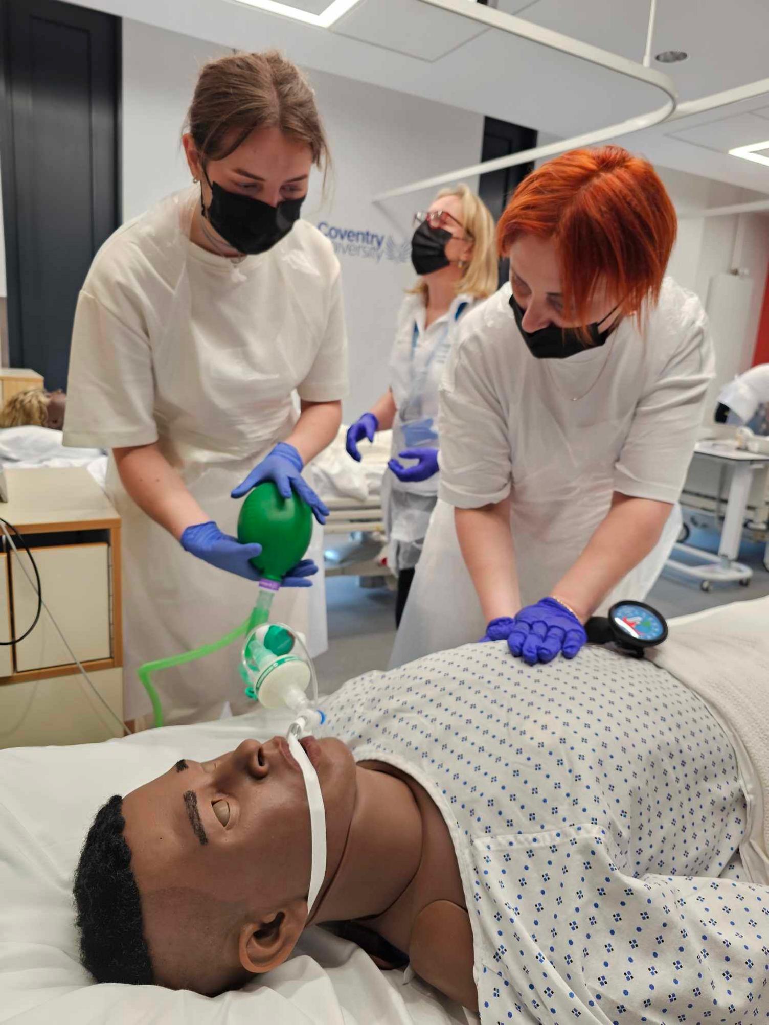 Two people practicing medical treatment on a dummy