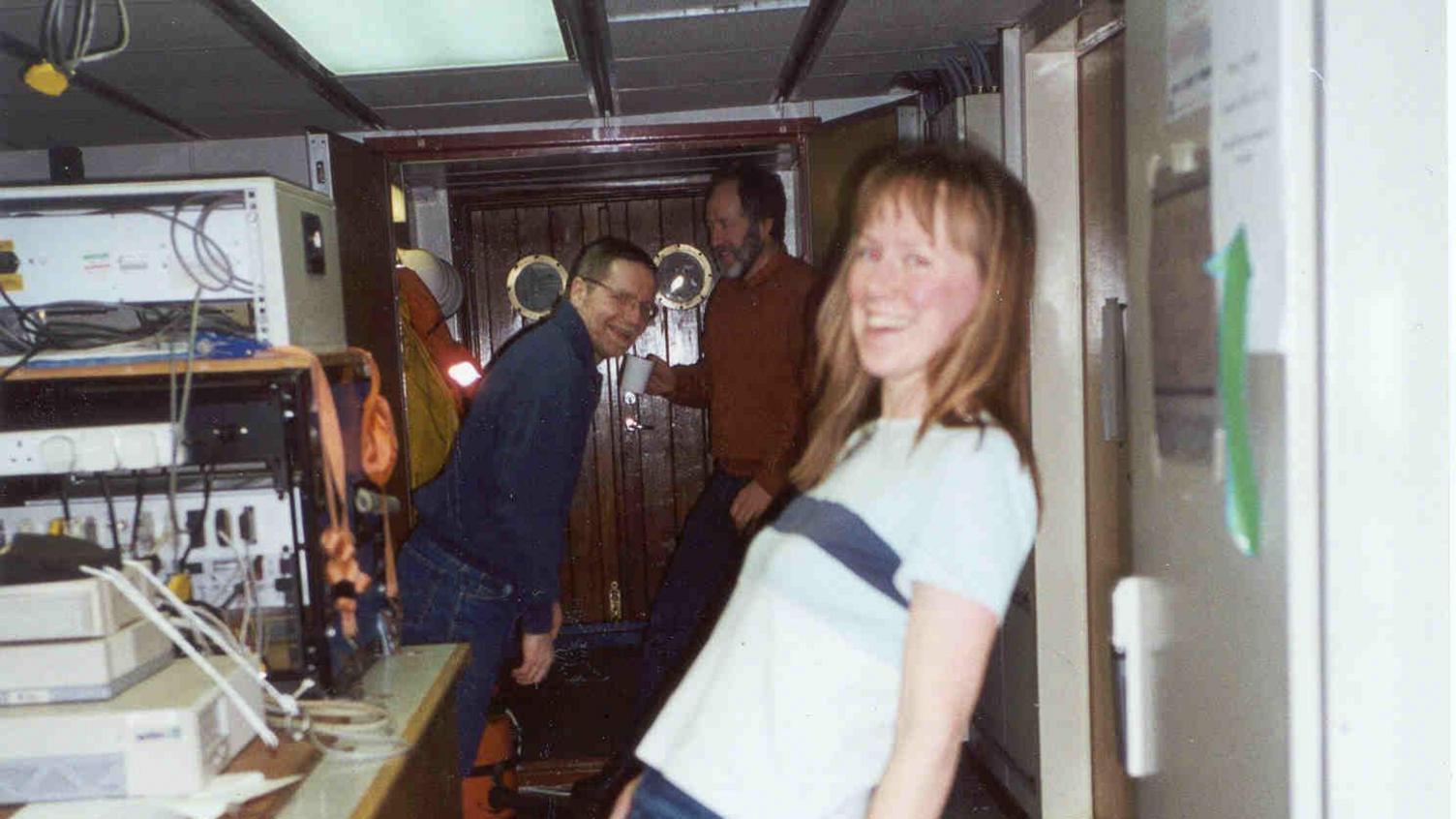 An old picture of Prof Holliday and two men leaning over whilst on board discovery.