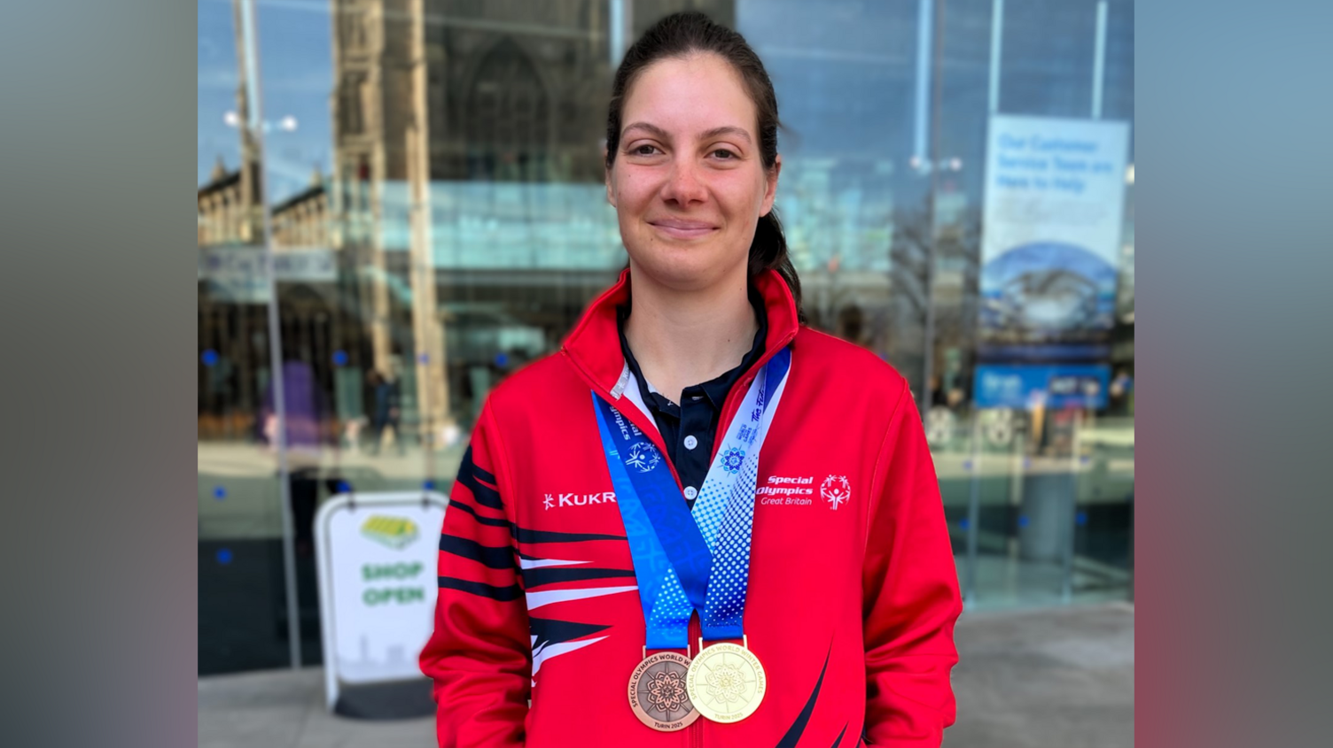 Annabelle Lamb in a red training top, with a gold and bronze medals around her neck on blue and white ribbons