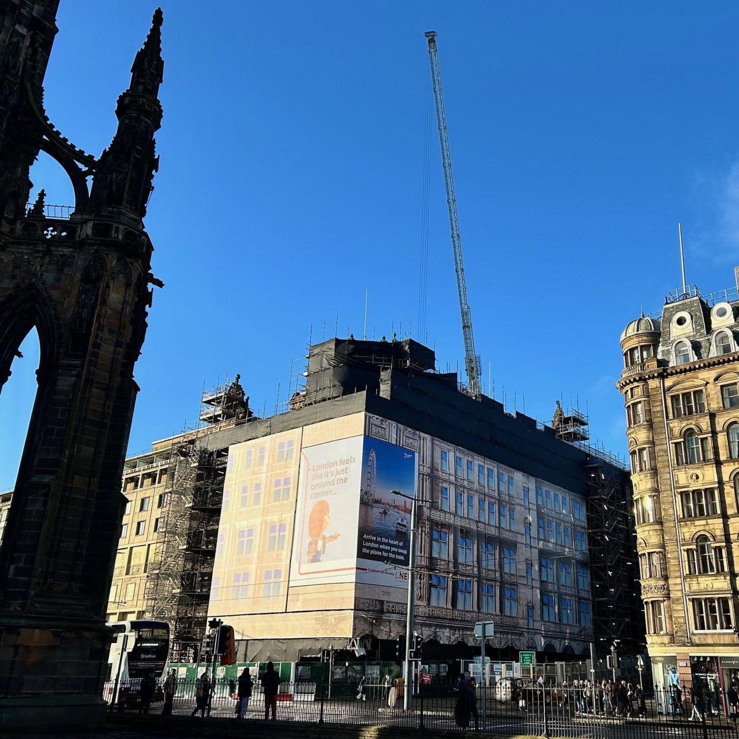 A crane is poking through the roof set against a blue sky. 