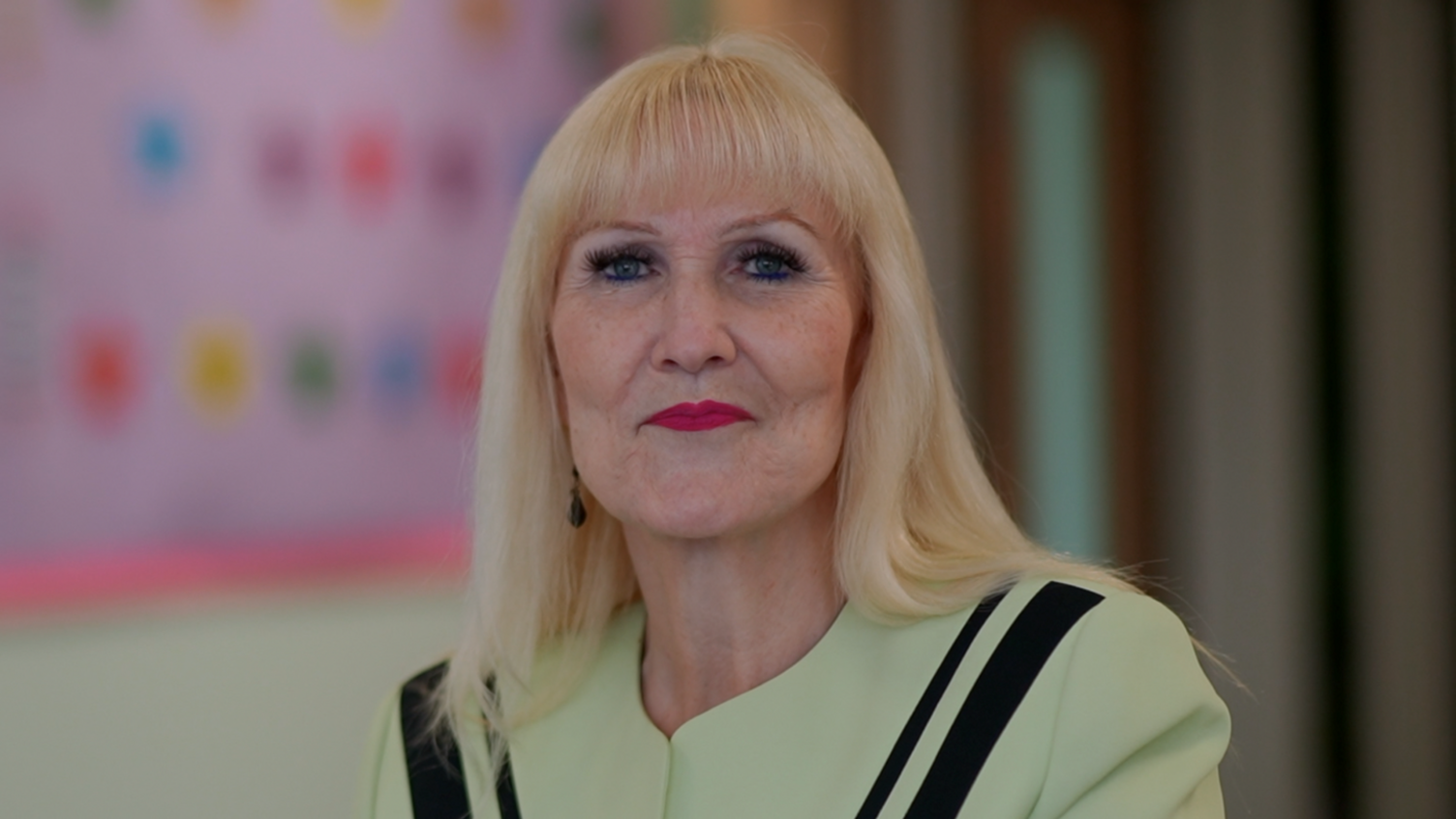 Sue Jackson, who is smiling at the camera. She is wearing a green top with black stripes.