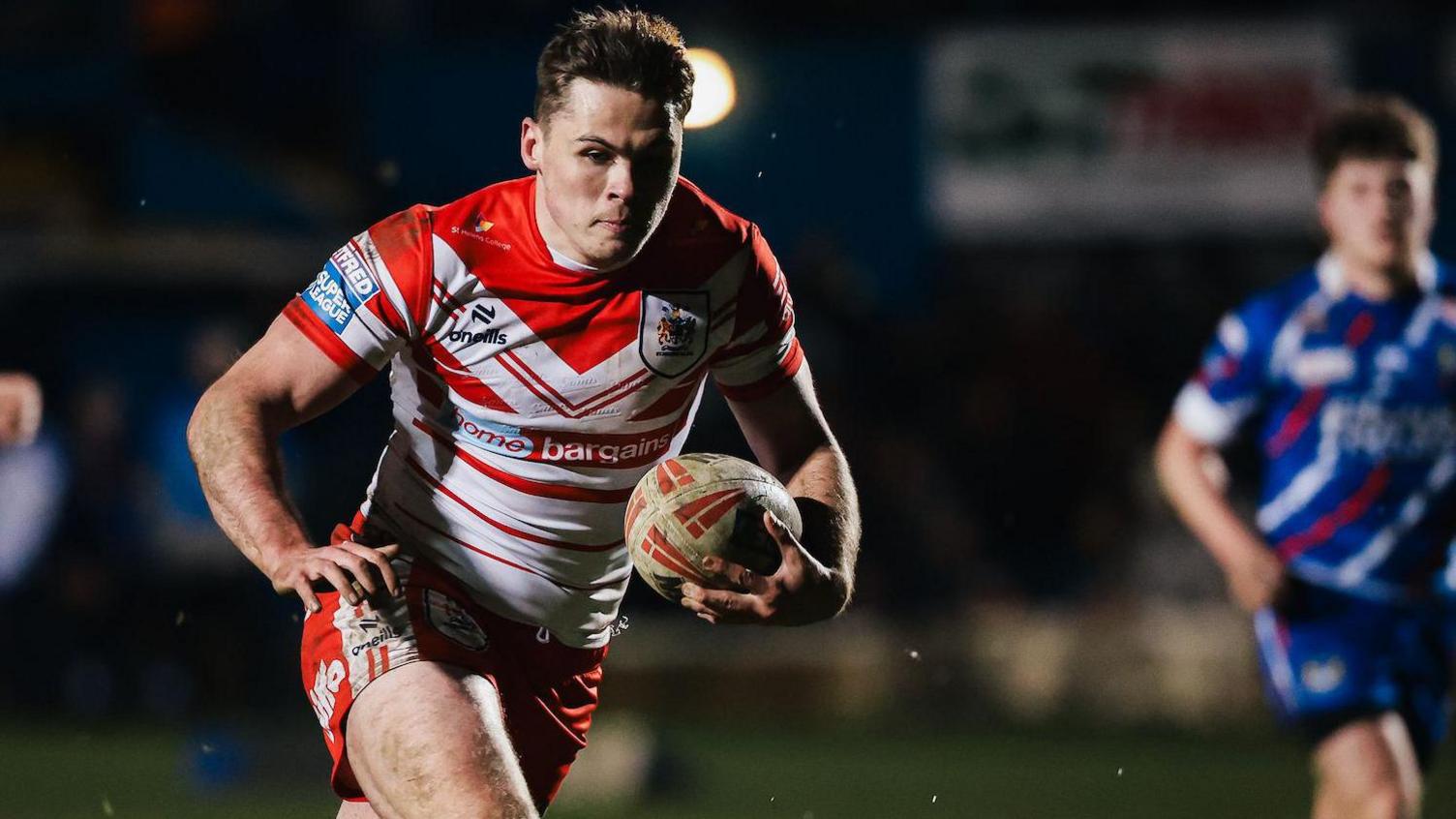 Jack Welsby runs with the ball in one hand, primed to fend away a defender with the other