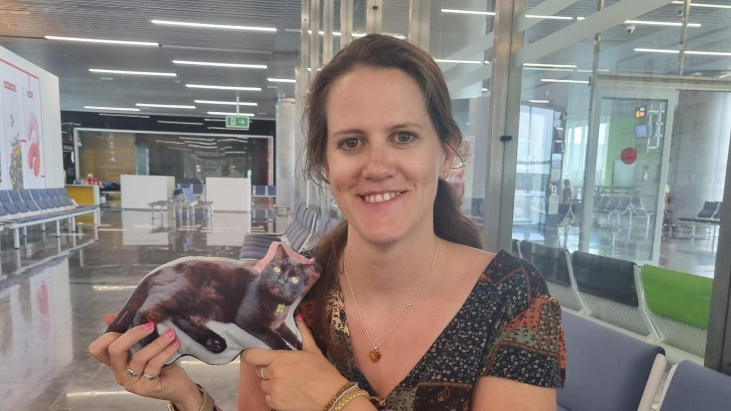 Mali Hill holding a small cushion with a picture of Reggie the cat