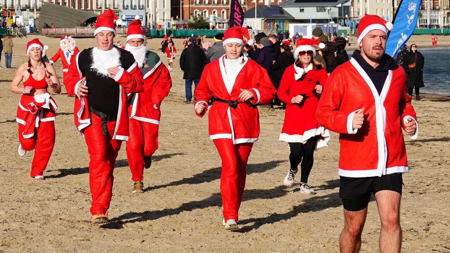 Runners dressed as santa running on the beach