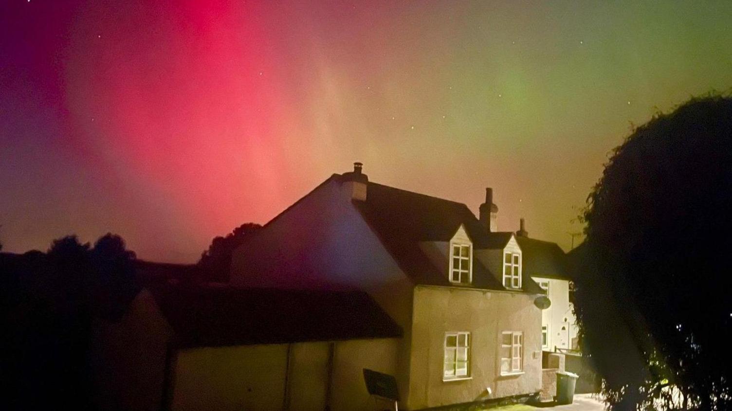 House in the foreground of the photo, with red and green tinges in the sky.