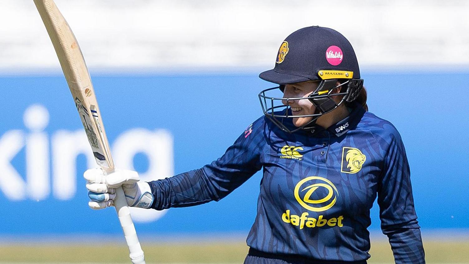 Durham batter Mia Rogers holds her bat aloft after reaching 50 against Essex