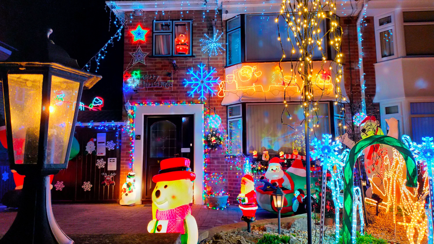 The exterior of a house, covered with a large number of bright lights and other Christmas decorations.