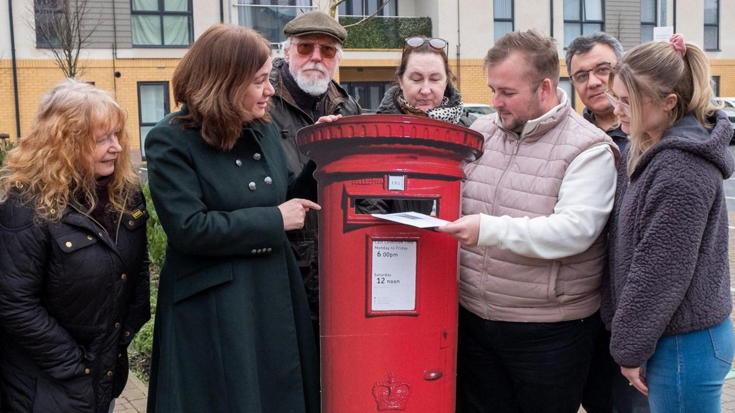 Labour MP Alex Mayer is stood with a group of residents with a cardboard cut out of a post box