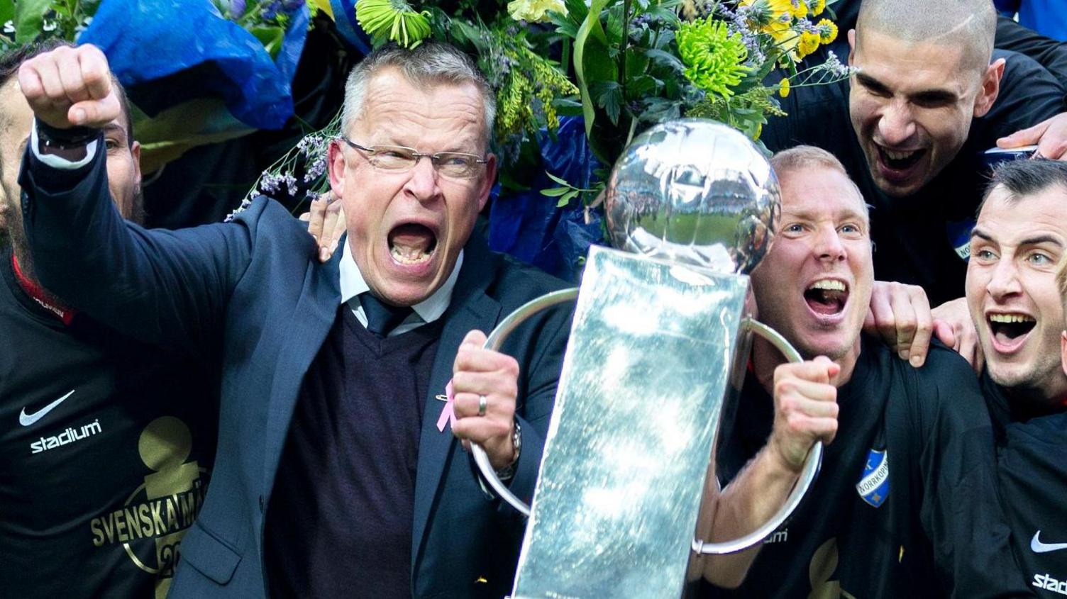 Janne Andersson screams in delight as he holds one handle of the Allsvenskan trophy