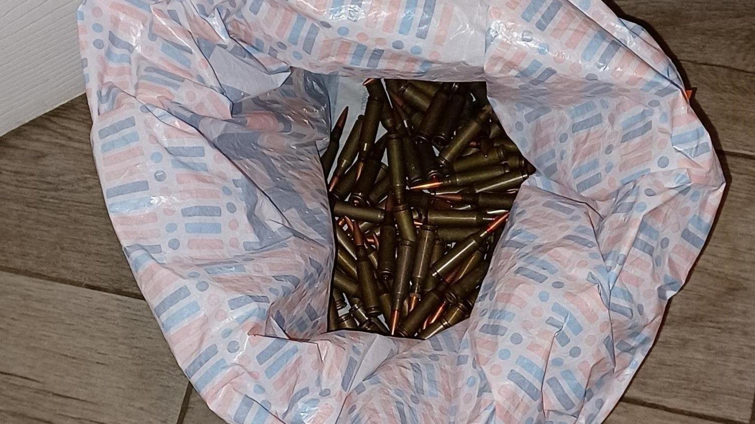 A plastic carrier bag containing a large number of bullets.