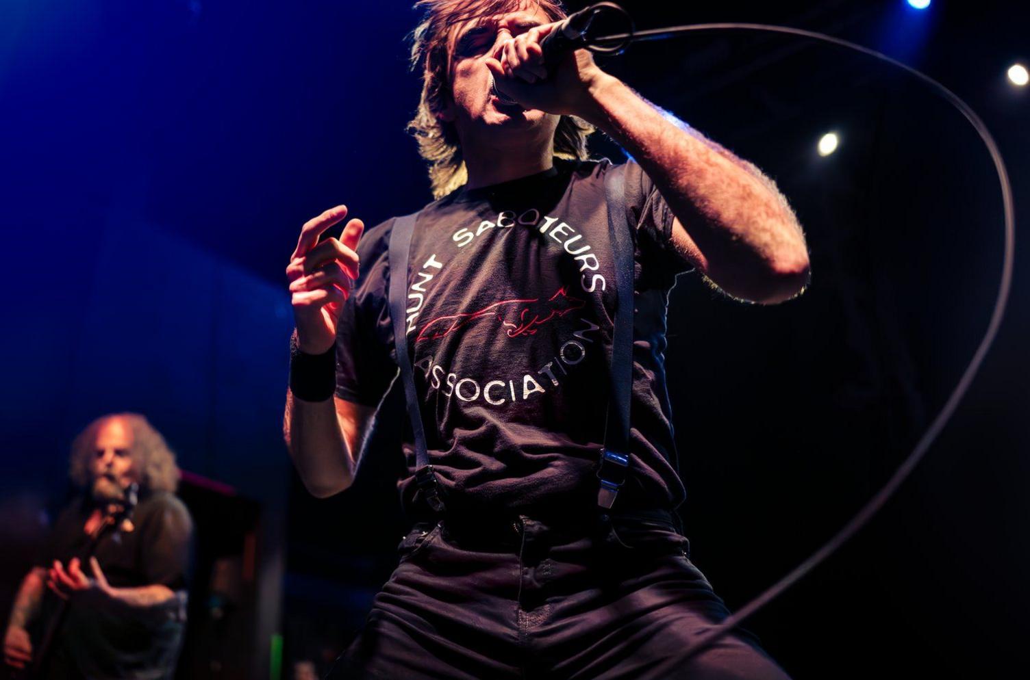 A singer holding a microphone wears a t-shirt which says Hunt Saboteurs Association