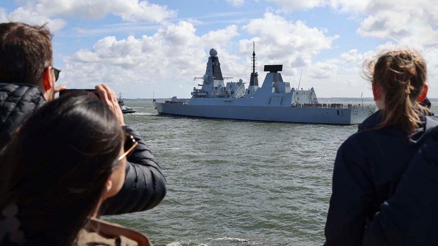 HMS Diamond being watched by people in Portsmouth as it sets sail for the Middle East