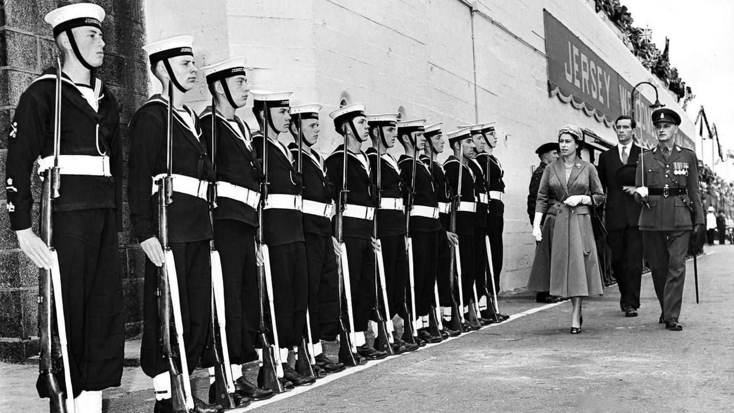 A black and white photo shows Queen Elizabeth approaching members of Jersey Sea Cadets