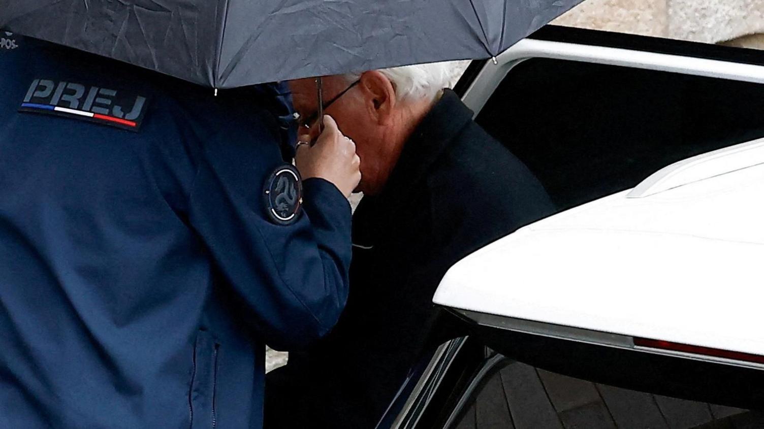 An elderly man is escorted out of car by police