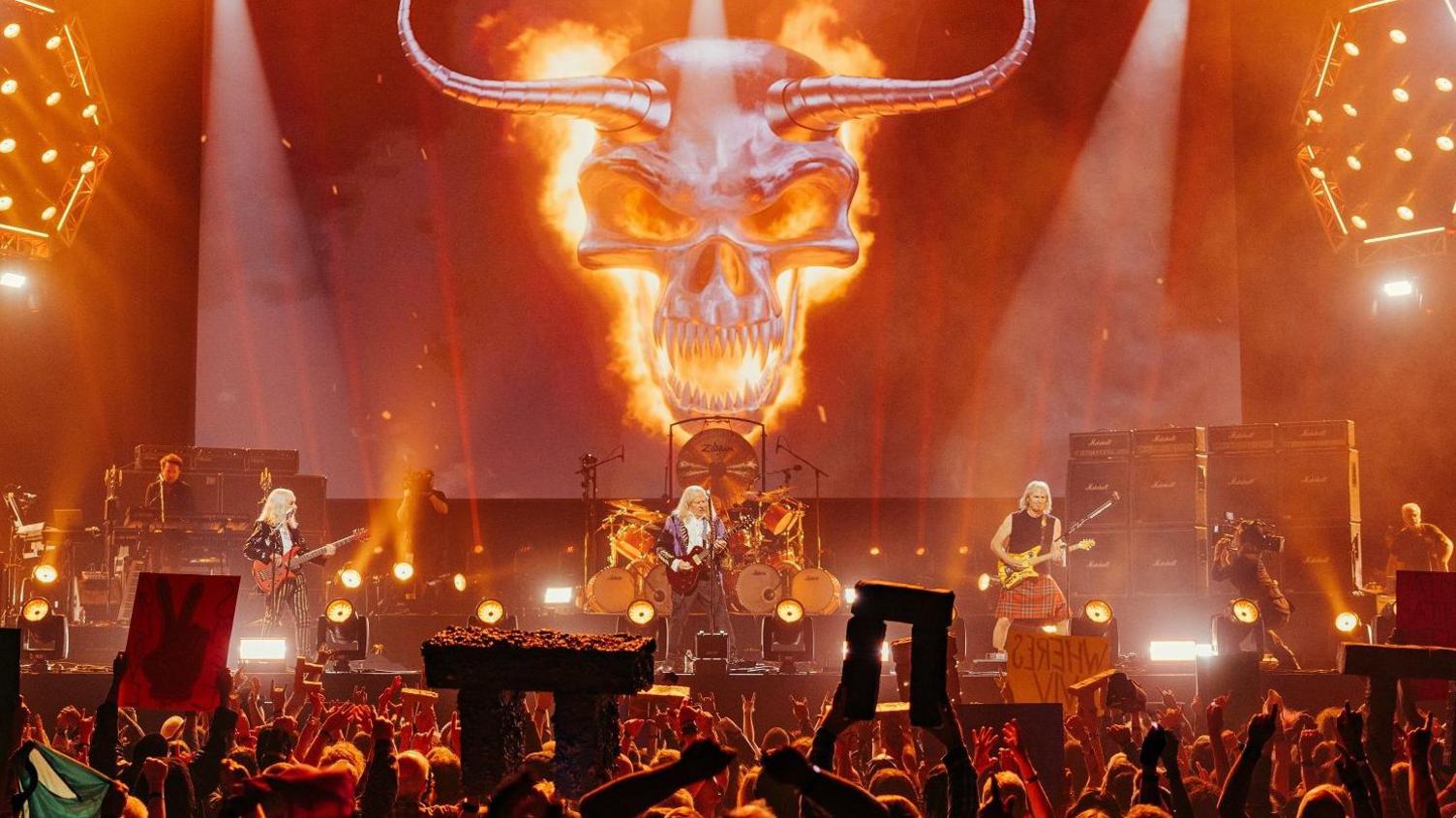 Spinal Tap playing live while fans holding up minituare Stone Henge replicas