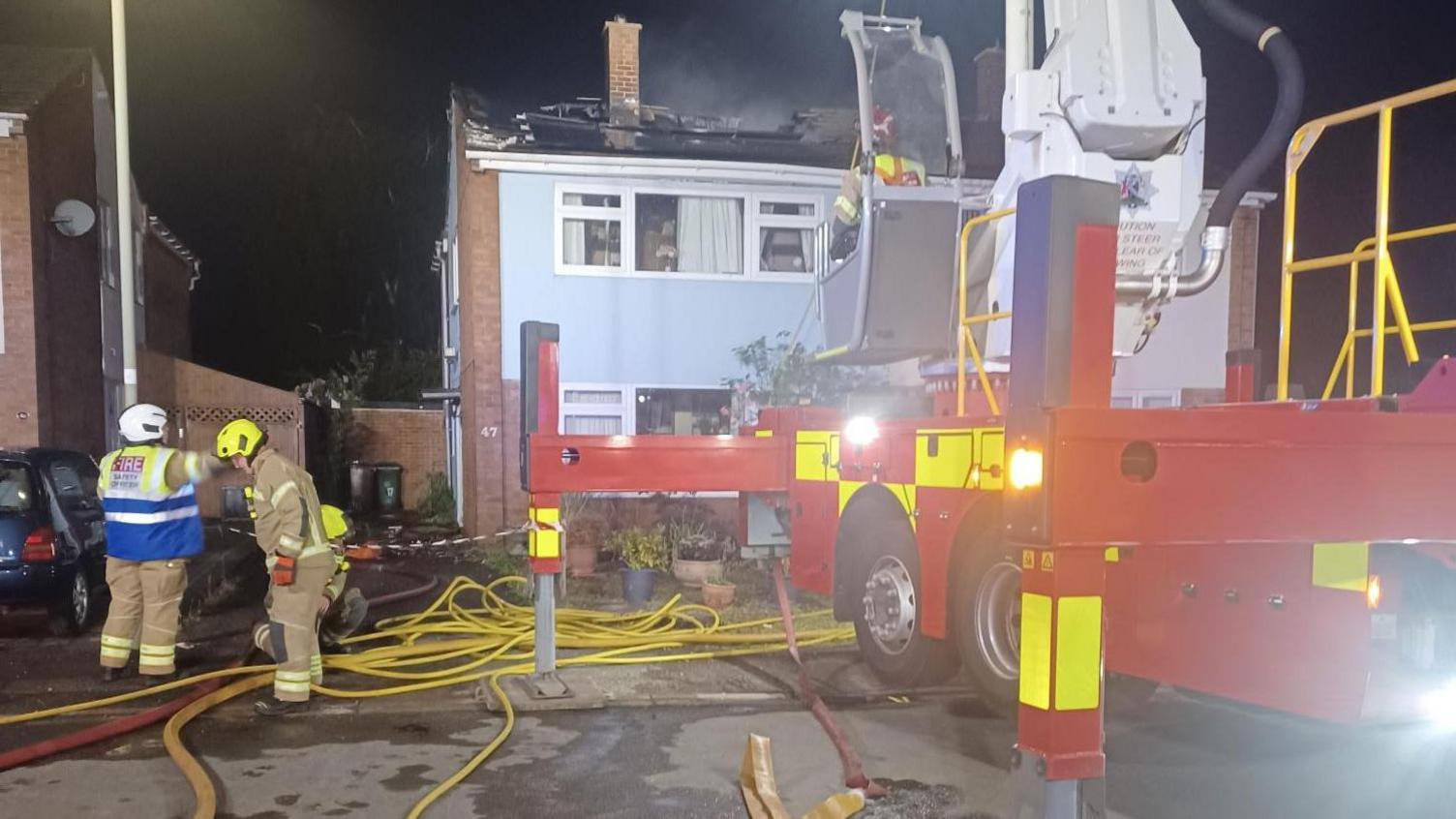 Fire crews attending to the incident and a fire engine outside the affected property at night