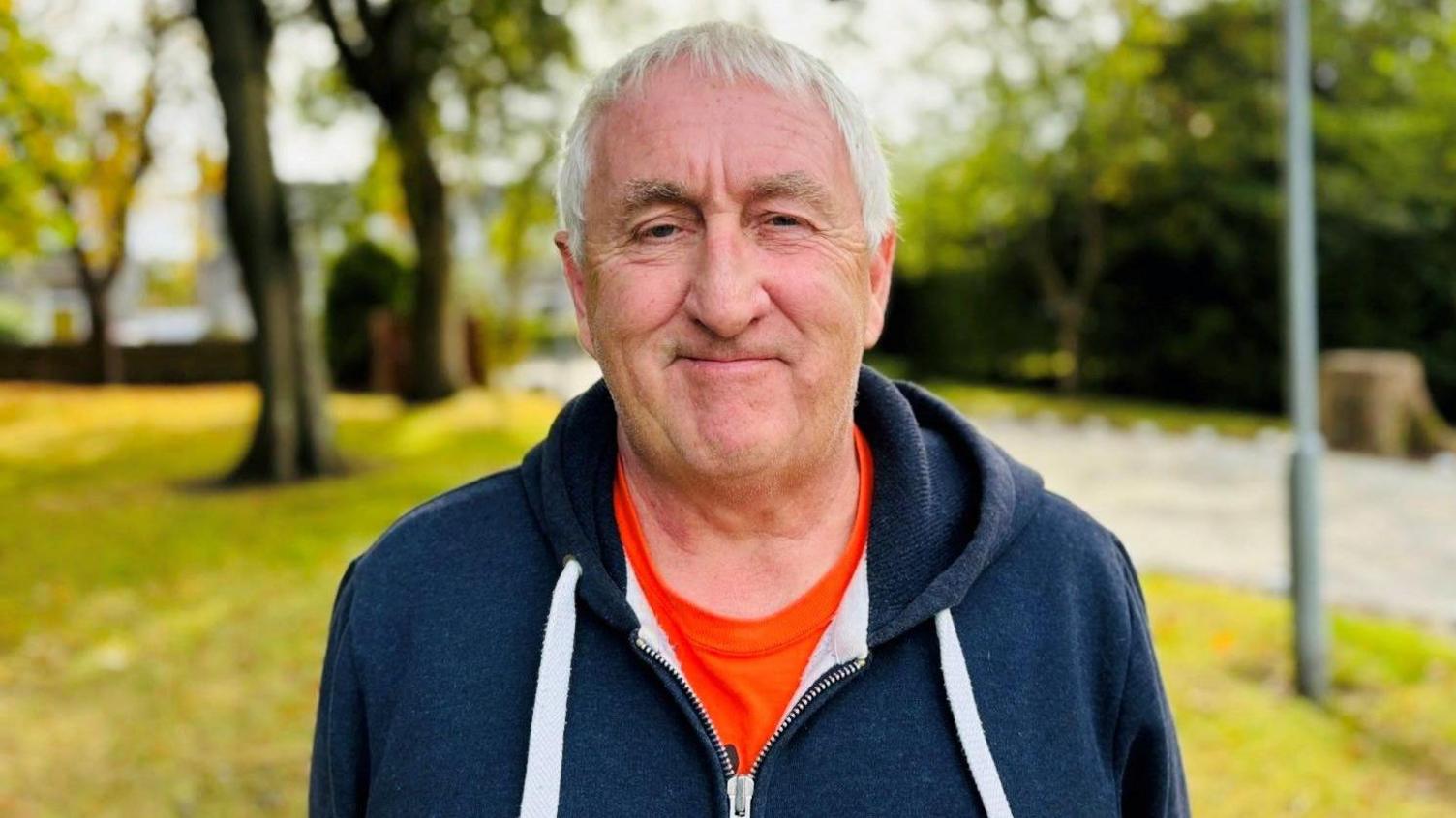 Terry Cheyne, smiling, with trees in background