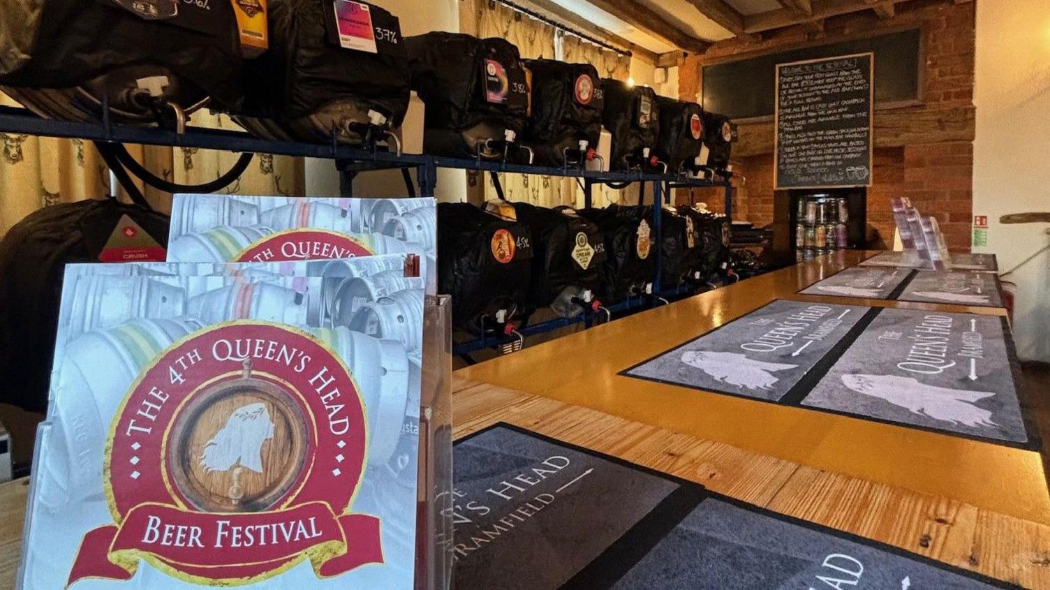 Barrels of real ale are stacked beside a bar with beer mats on and leaflets for beer festival