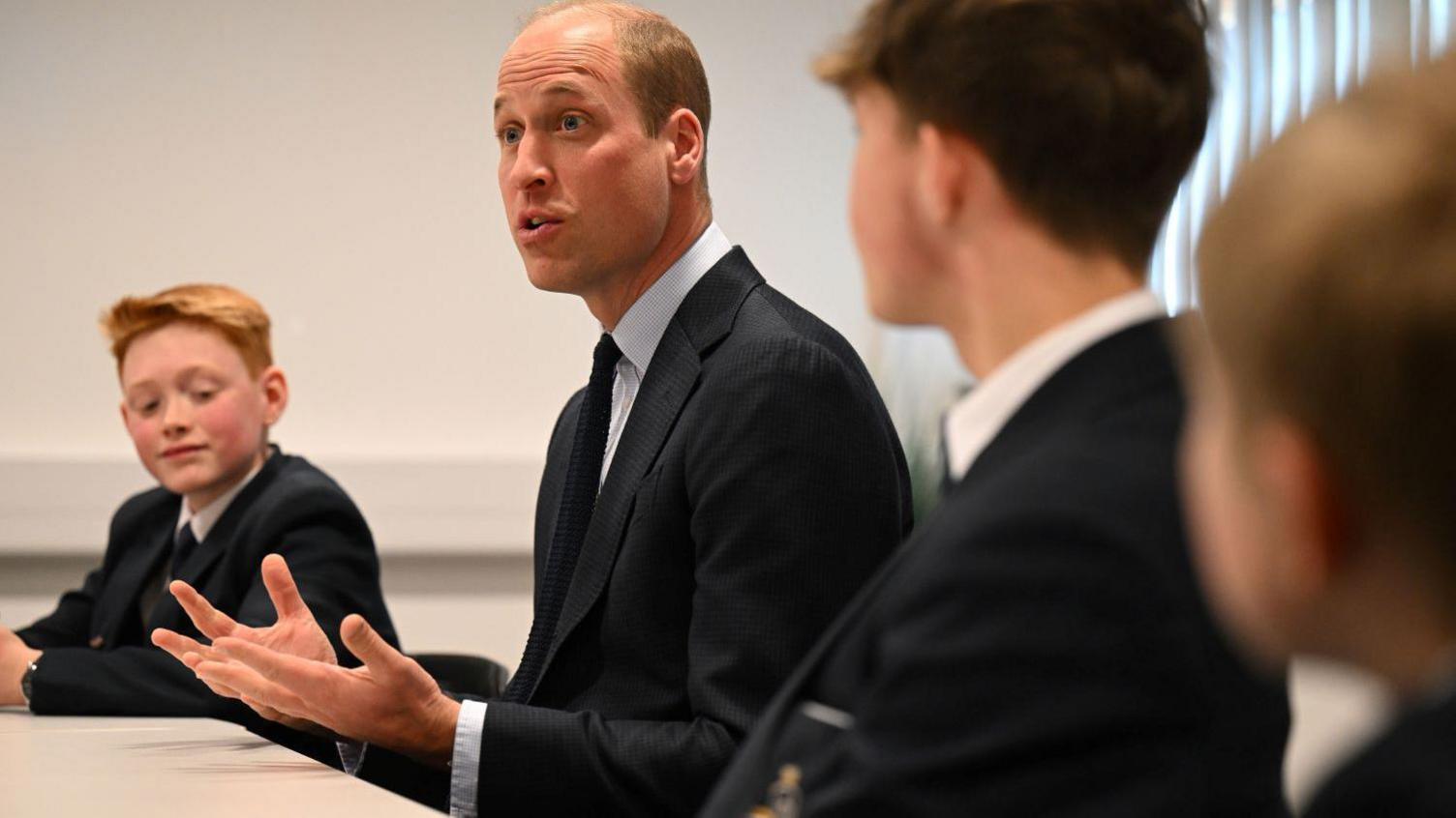 Prince William speaking to pupils round a table