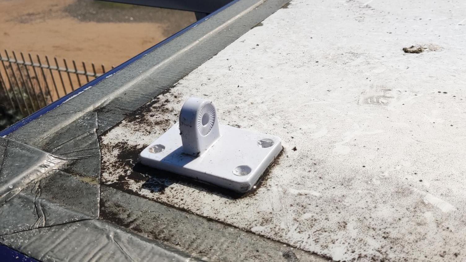 A plastic base of an aerial sits empty on a roof