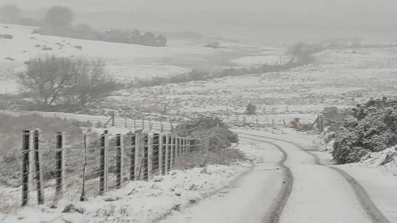 A road near Jamaica Inn set in the moors is covered in snow.