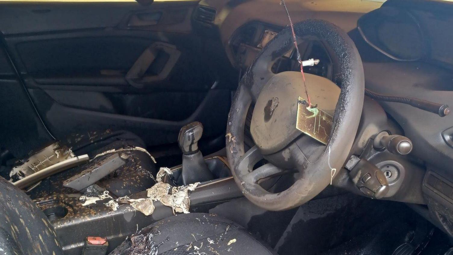 The steering wheel and burnt front seats of the car