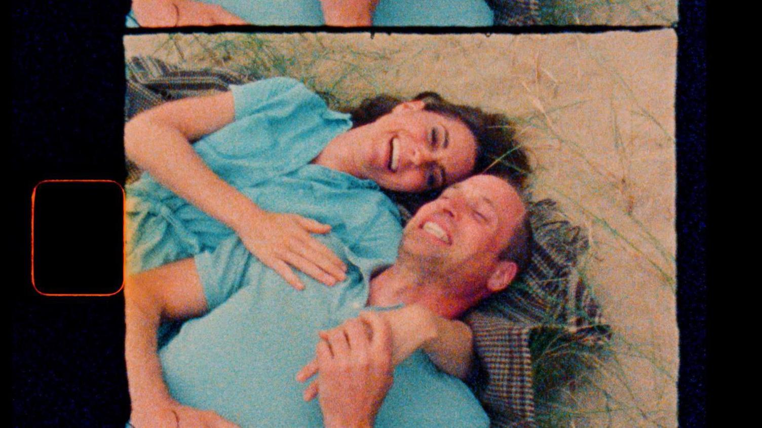 The Prince and Princess of Wales lie down together on a blanket on a beach