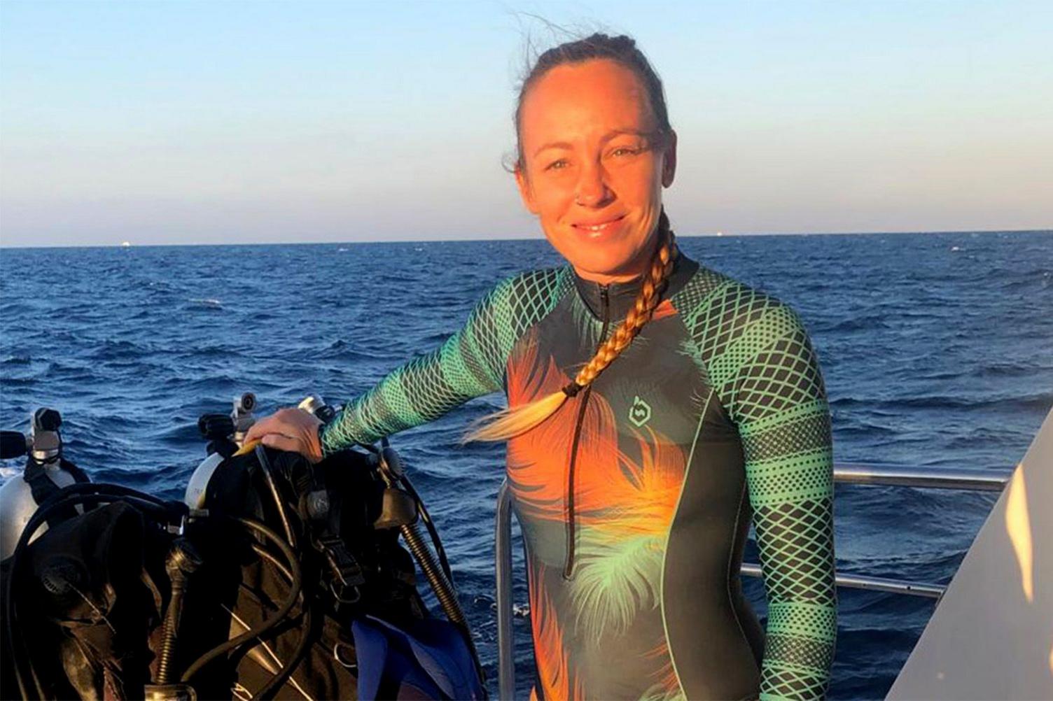 Hissora Gonzalez standing on a boat at sea in a green and orange wetsuit.