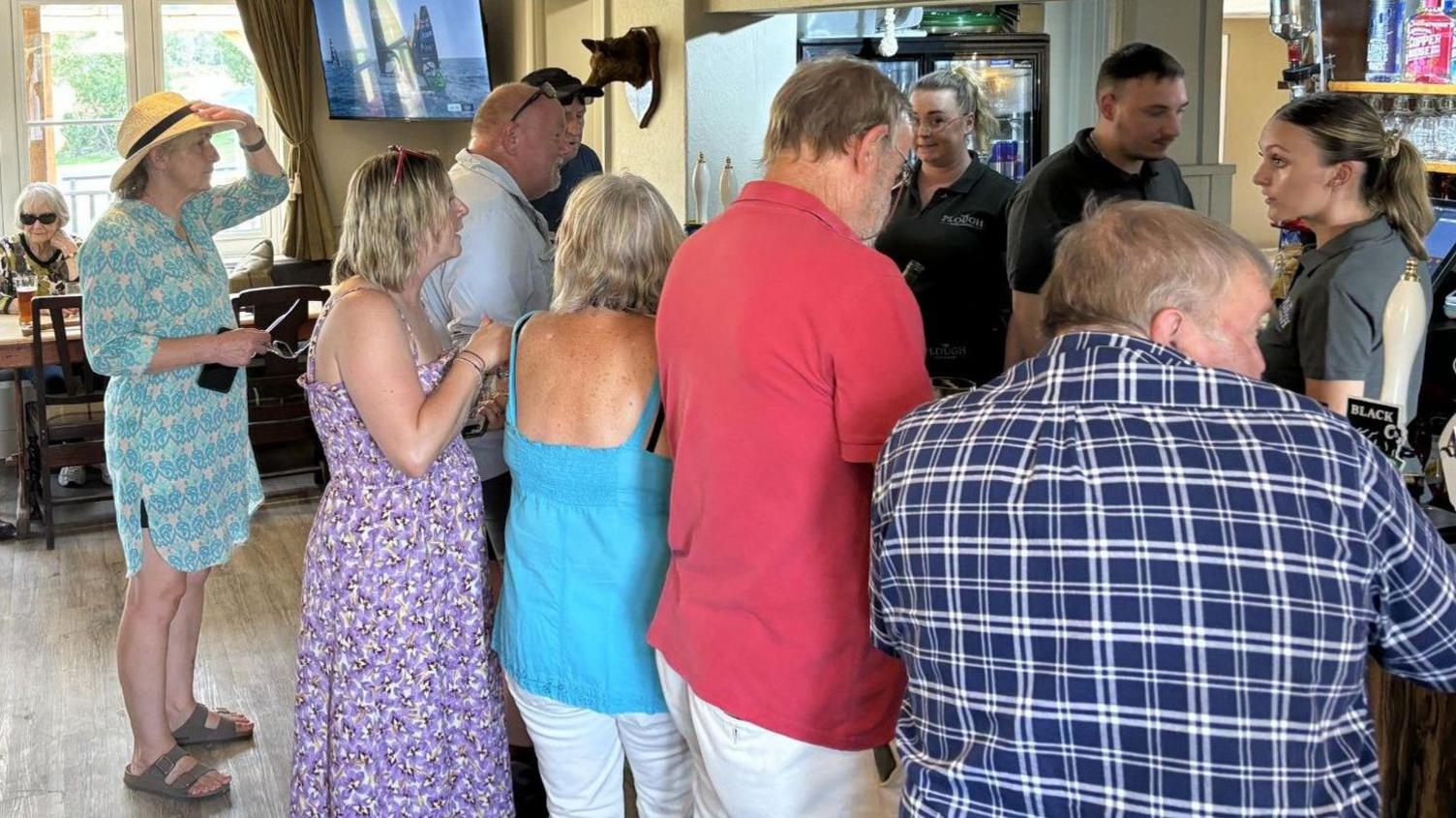 A group of people queuing up to buy drinks in a pub