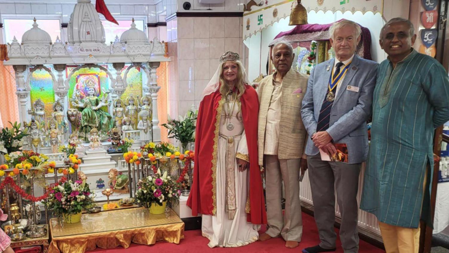 A woman and three men are standing next to a white shrine