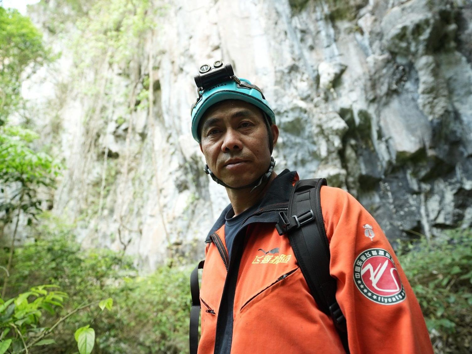 Brother Fei in an orange jacket and blue helmet 