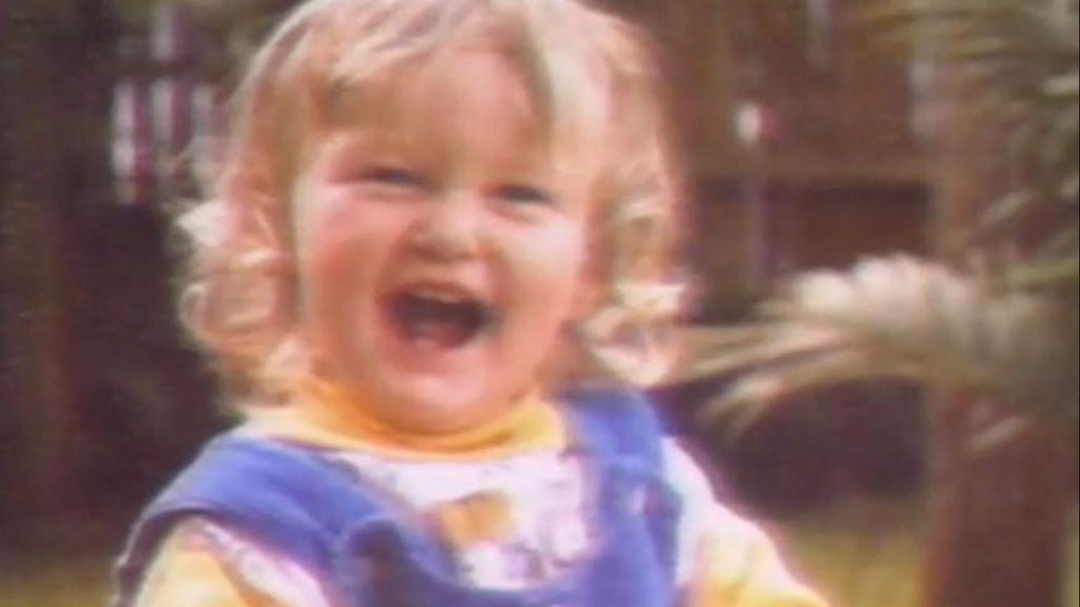 A laughing toddler with shoulder length blonde hair