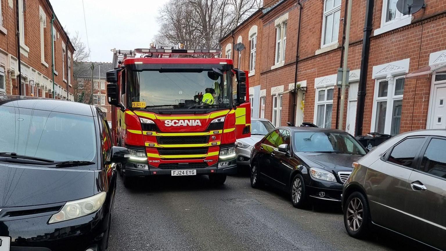 A fire engine squeezing down a terraced road with double parking