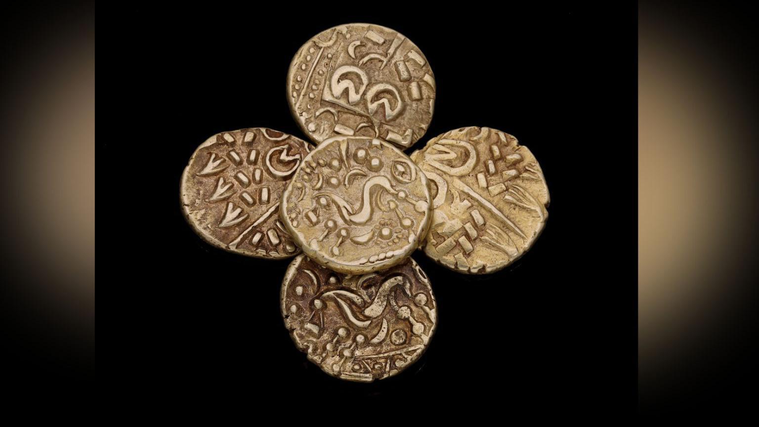 Four gold coins which date back from the Iron Age, with a black background