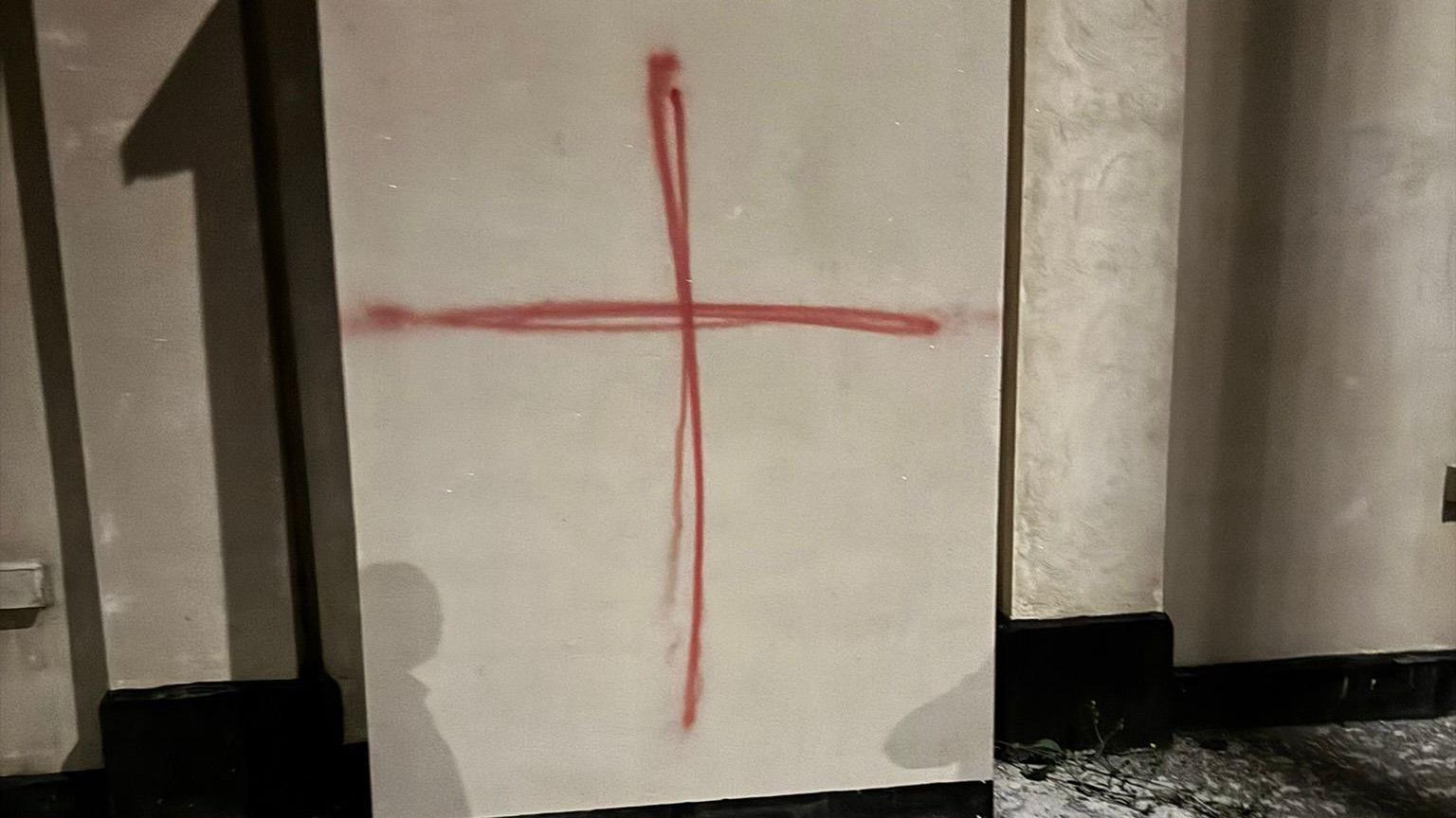A red St George's Cross has been painted onto a white wall of a building.