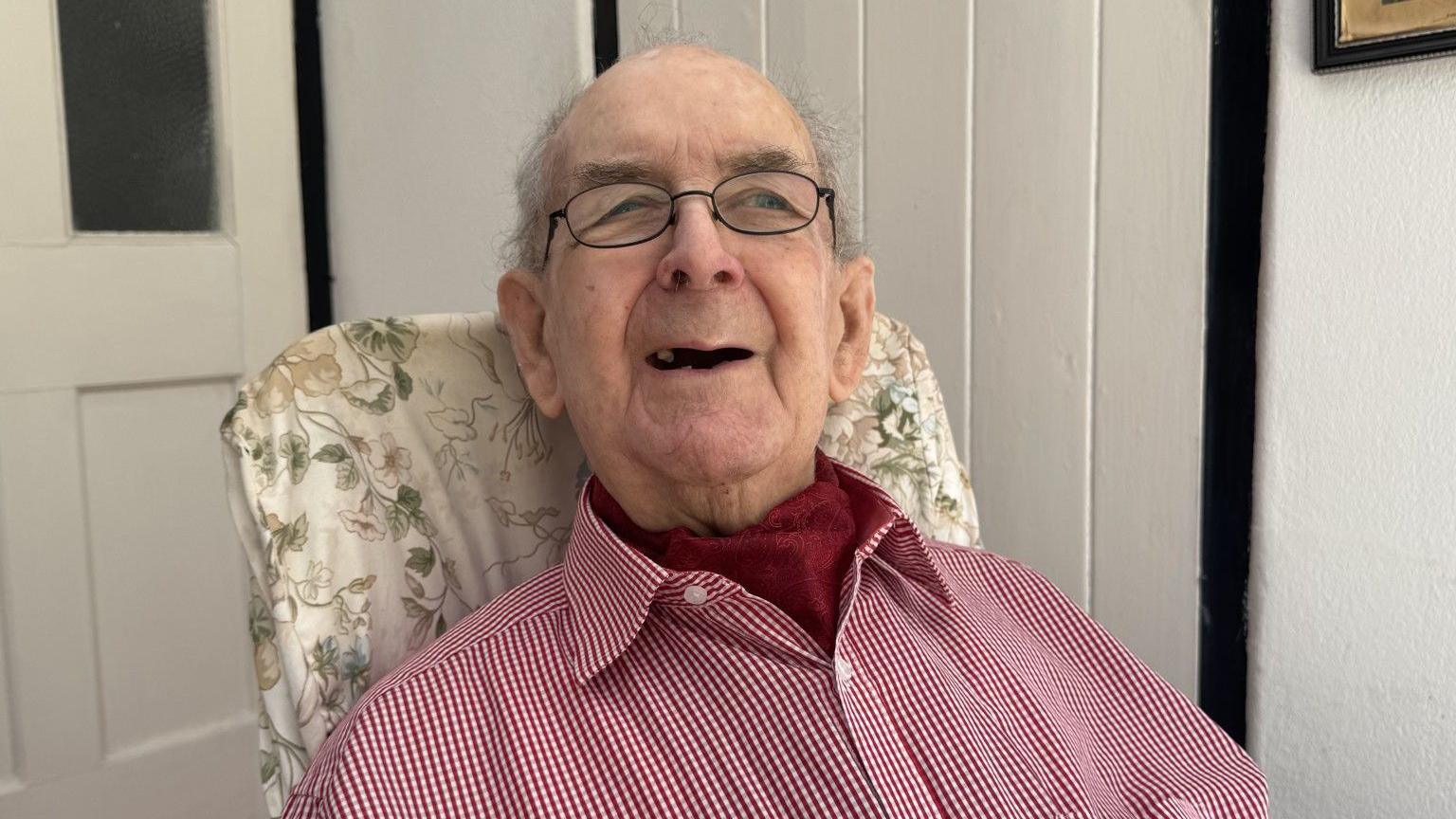 A close up of 96-year-old John Smith from Dover. He is wearing a red and white shirt and glasses.