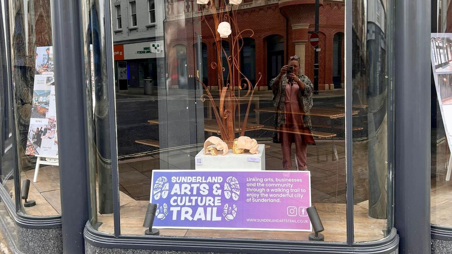 A shop window with a poster for Sunderland Arts and Culture Trail 