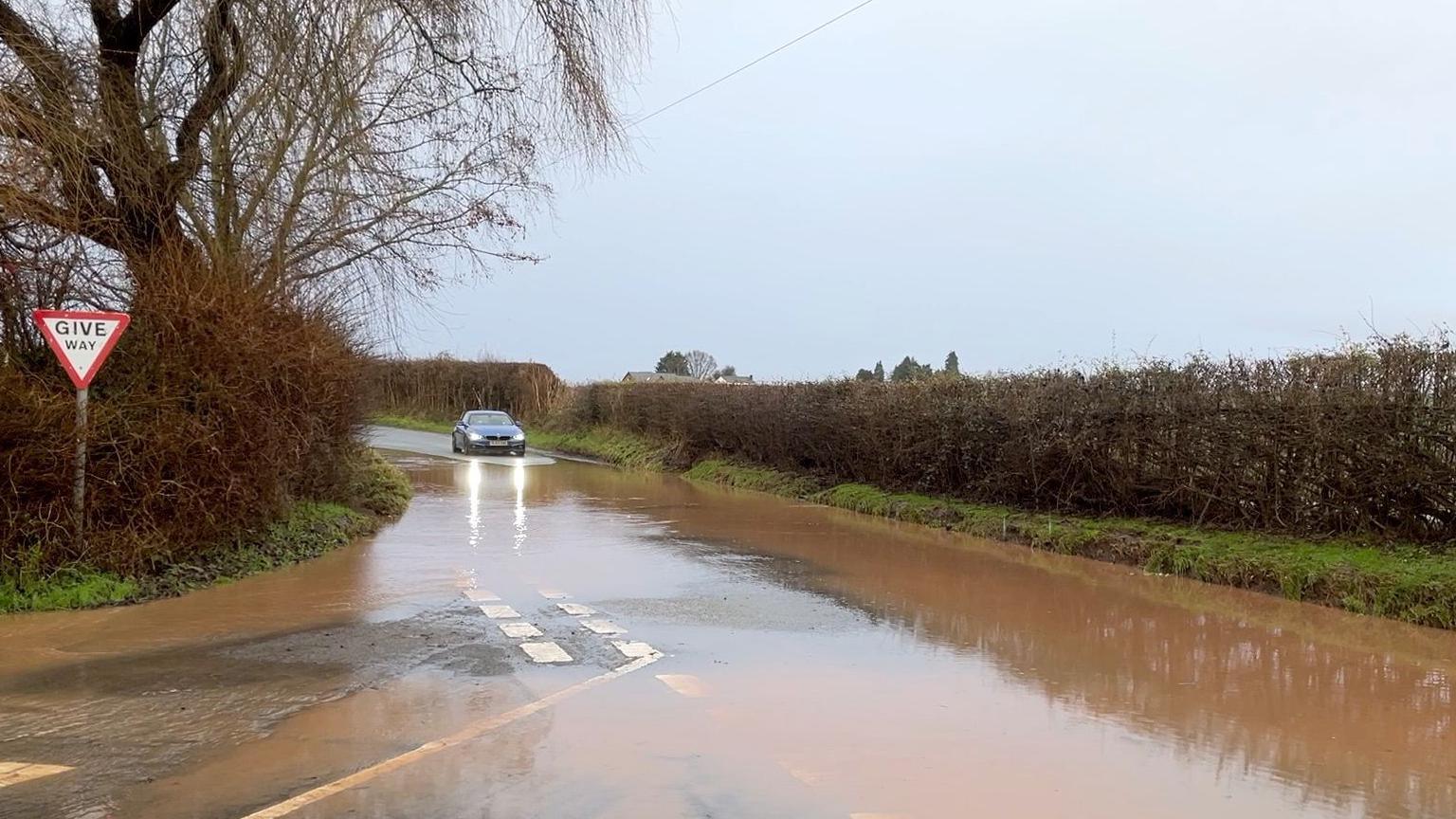 A car stops at a flooded road