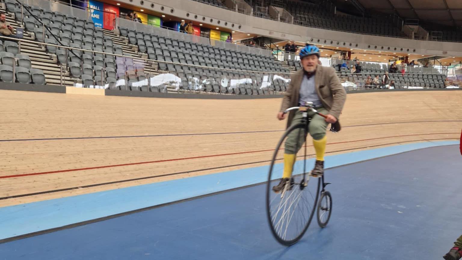 Mel Glass riding a penny farthing around a velodrome 