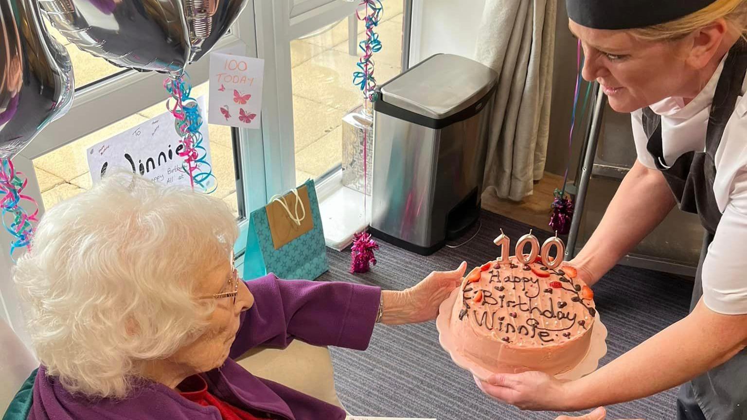 A cake being handed to Winnie Seeley