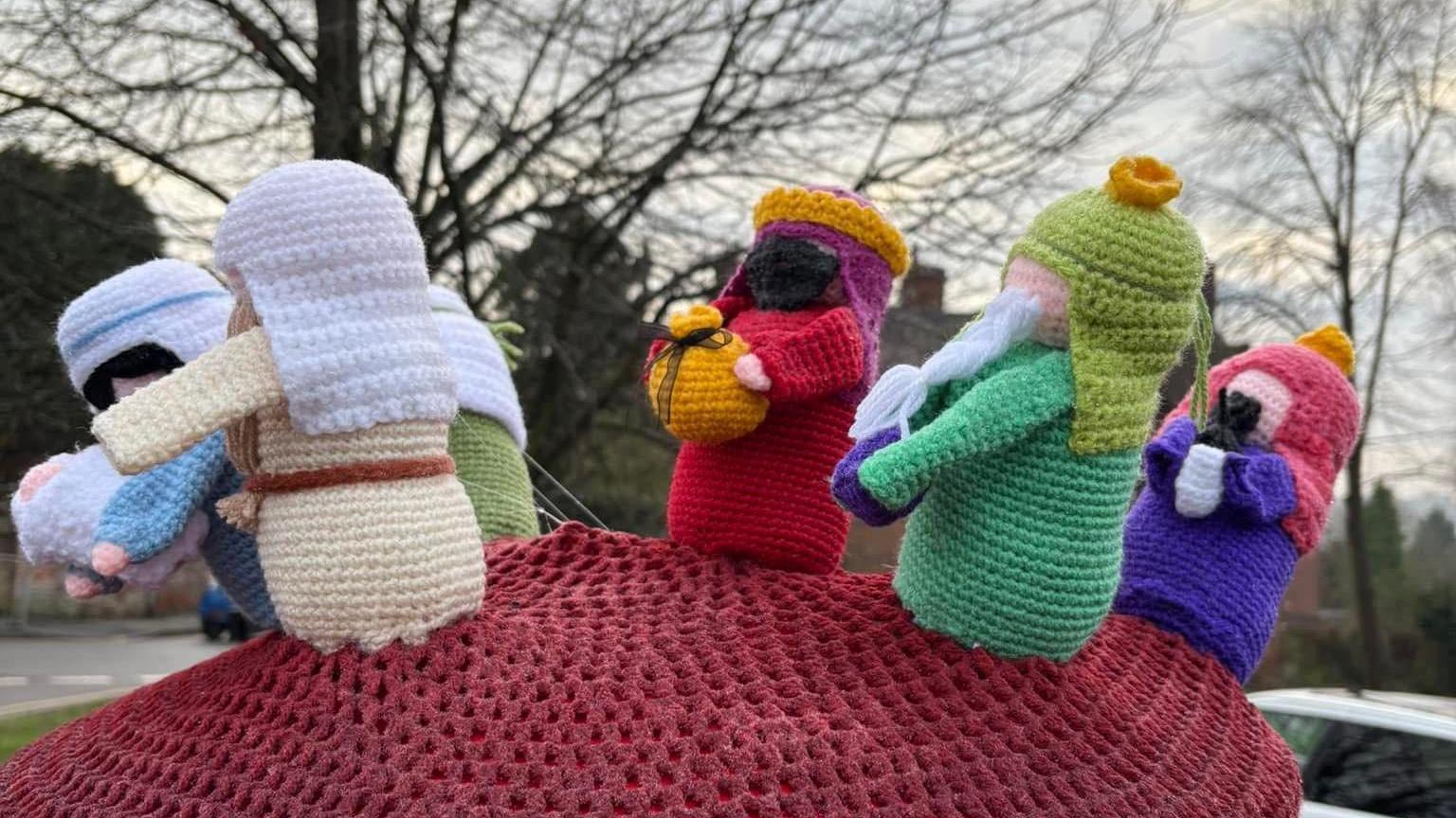 Knitted figures on a postbox in Wolverhampton include the three wise men bearing gifts and a figure carrying a baby at the front, representing Mary, Joseph and Jesus.