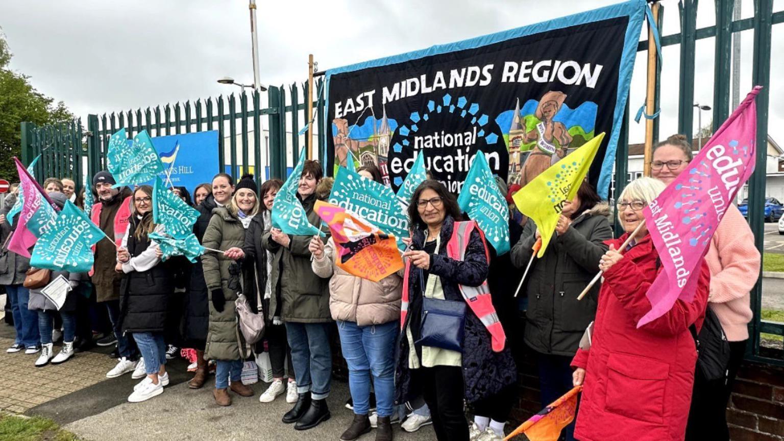 A group of teachers wave flags while striking