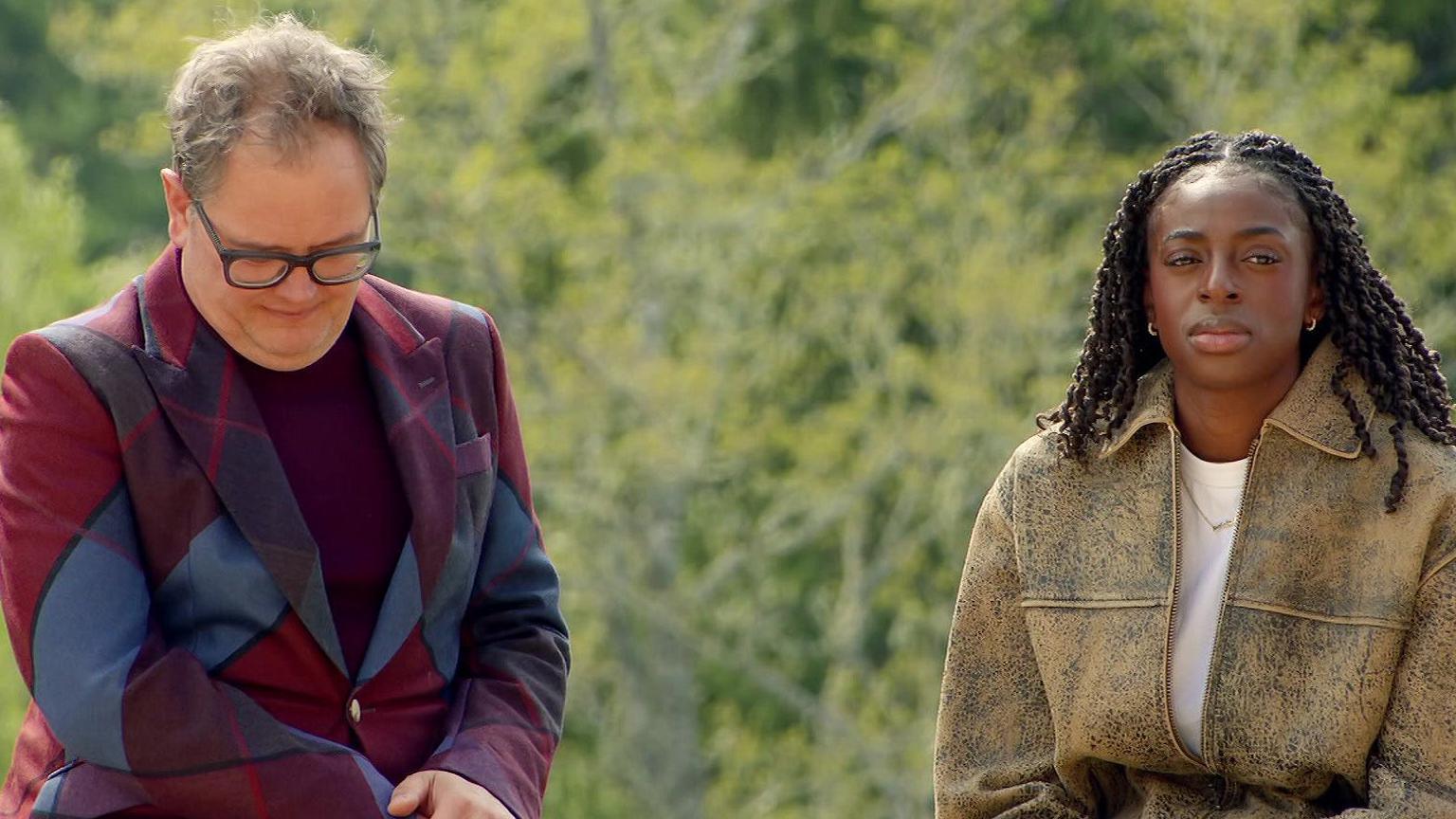 Alan Carr and Cat Burns sitting beside each other on the Traitors