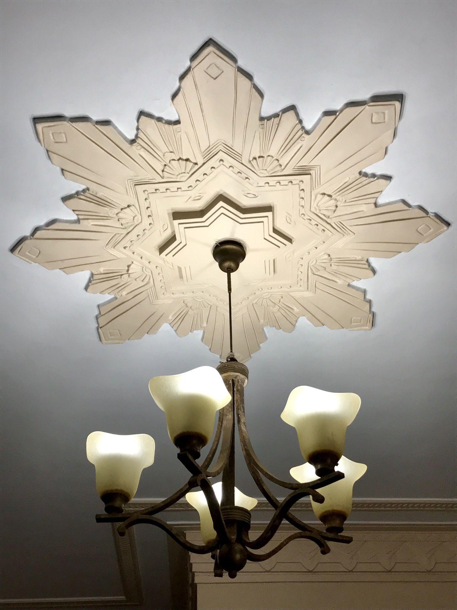 Example of Art Deco lighting at the Seksaria building in Marine Drive. The light has five bulbs in a candelabra-style fitting, with a geometric star design on the ceiling around it. 