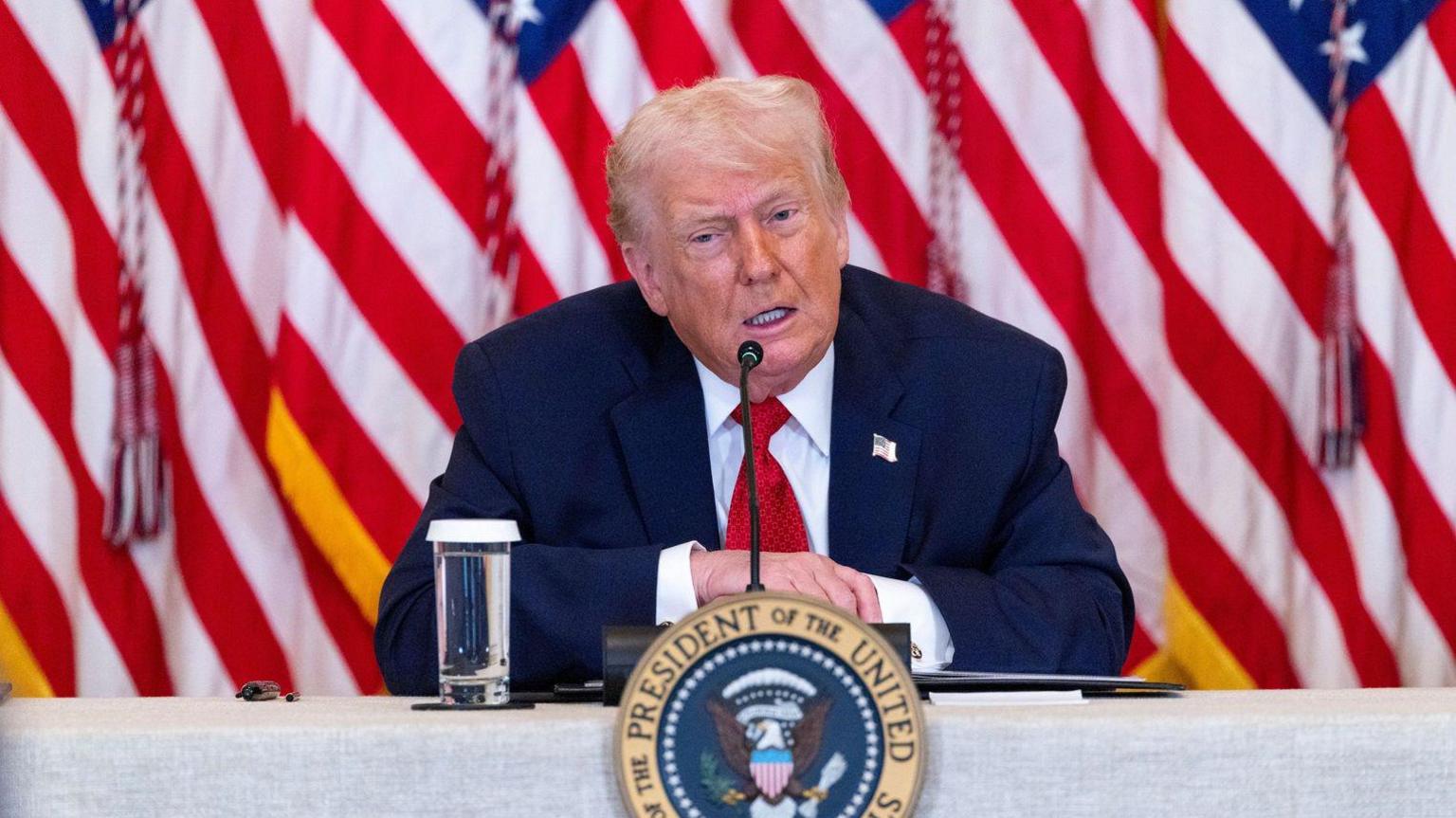 Donald Trump sitting at a desk