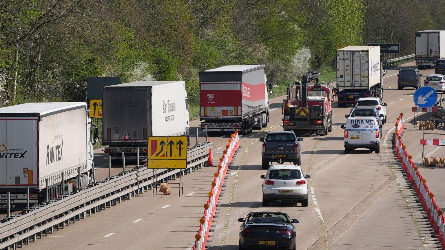 Queues of lorries and other vehicles travelling away from the camera on a motorway