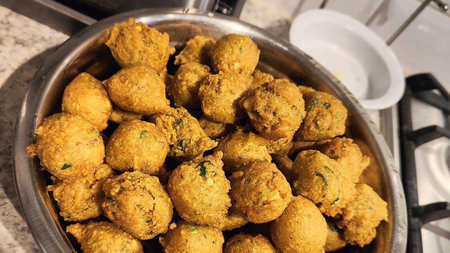 The a silver bowl full of the golden-coloured fried snack in a home kitchen.
