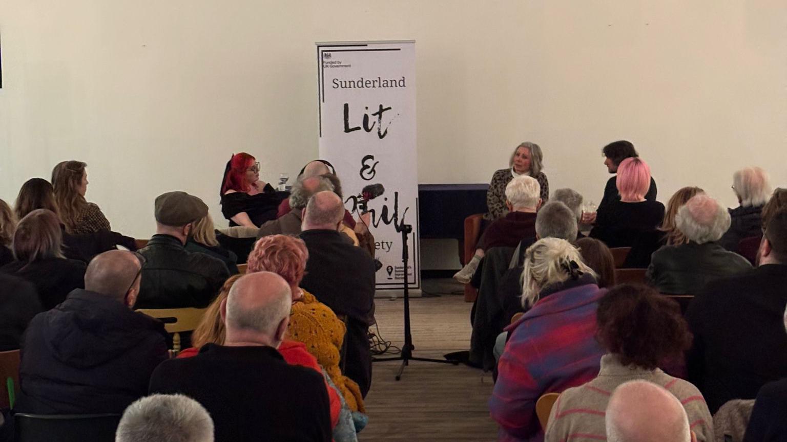 The backs of the audiences' heads who are facing the three people leading the discussion.