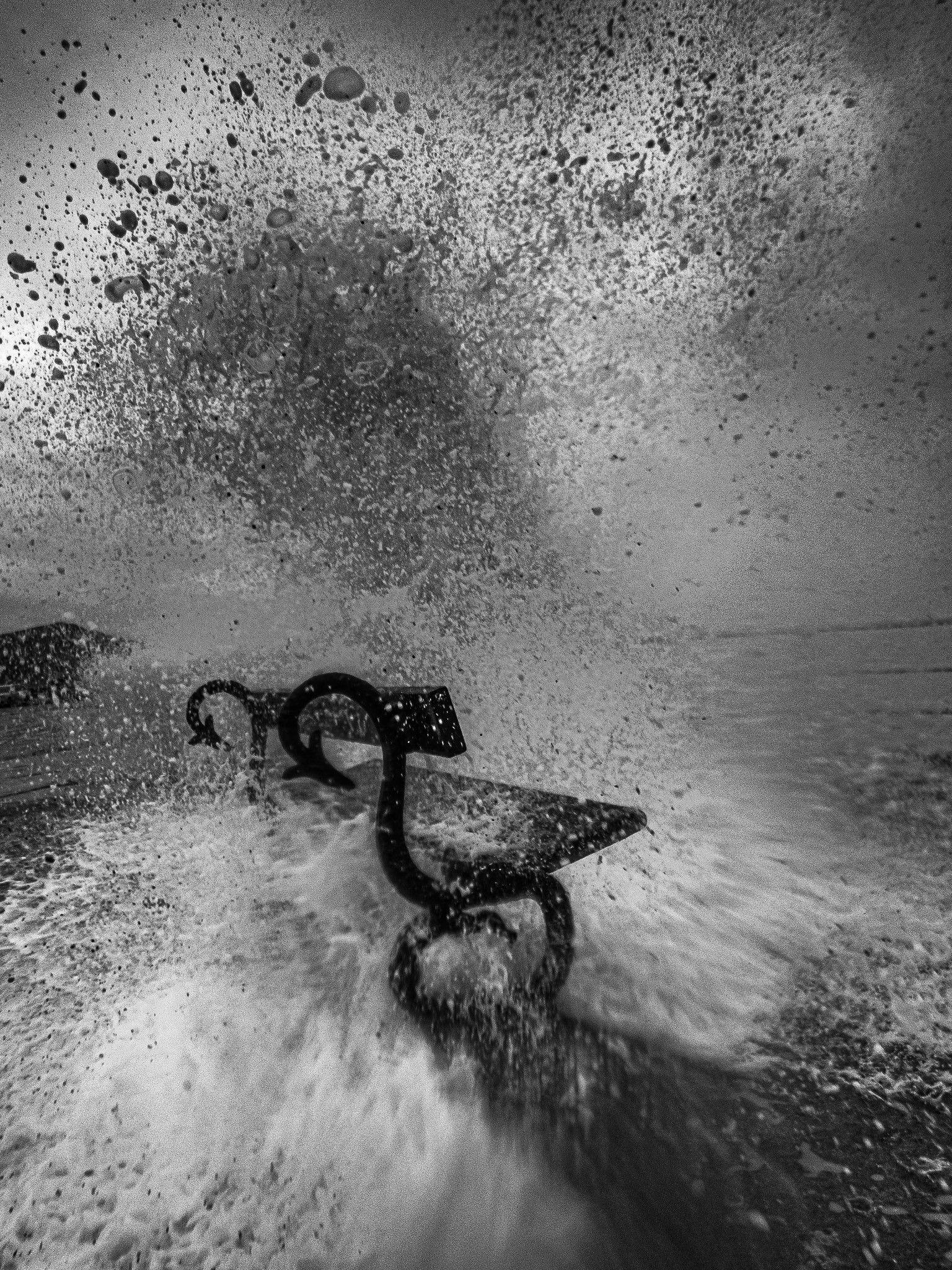 A wave breaks against a bench on the sea front