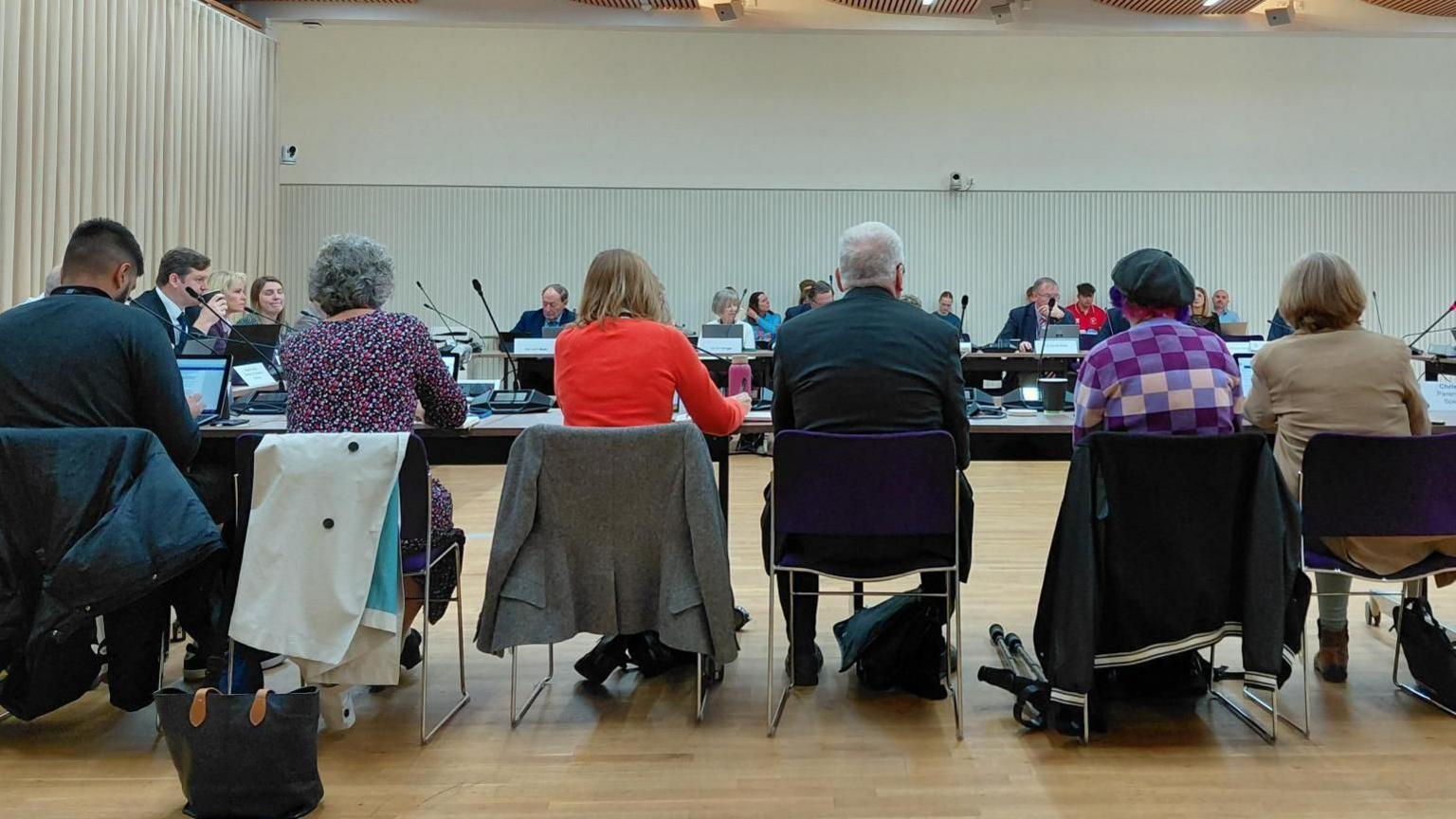 Councillors sit around desks shaped in a square formation as they discuss matters at the committee.